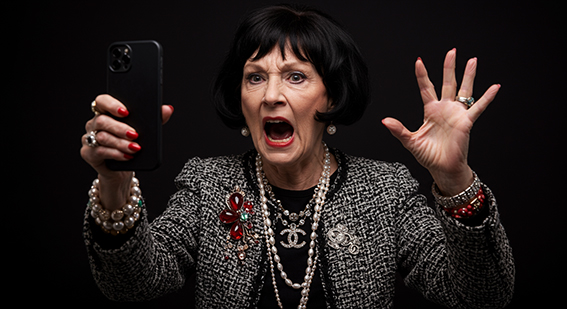 Nasty old woman shouting and holding up her cellphone.